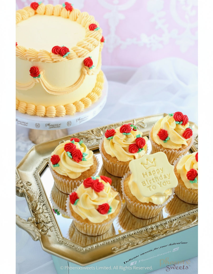A themed party cake and cupcakes with white buttercream frosting, decorated with red and green icing on a silver platter, with a larger cake in the background.
