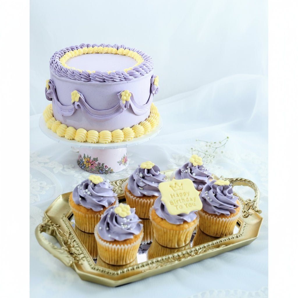 A themed birthday cake and cupcakes with butter cream icing in purple and yellow colors, arranged on a tray with a decorative background.