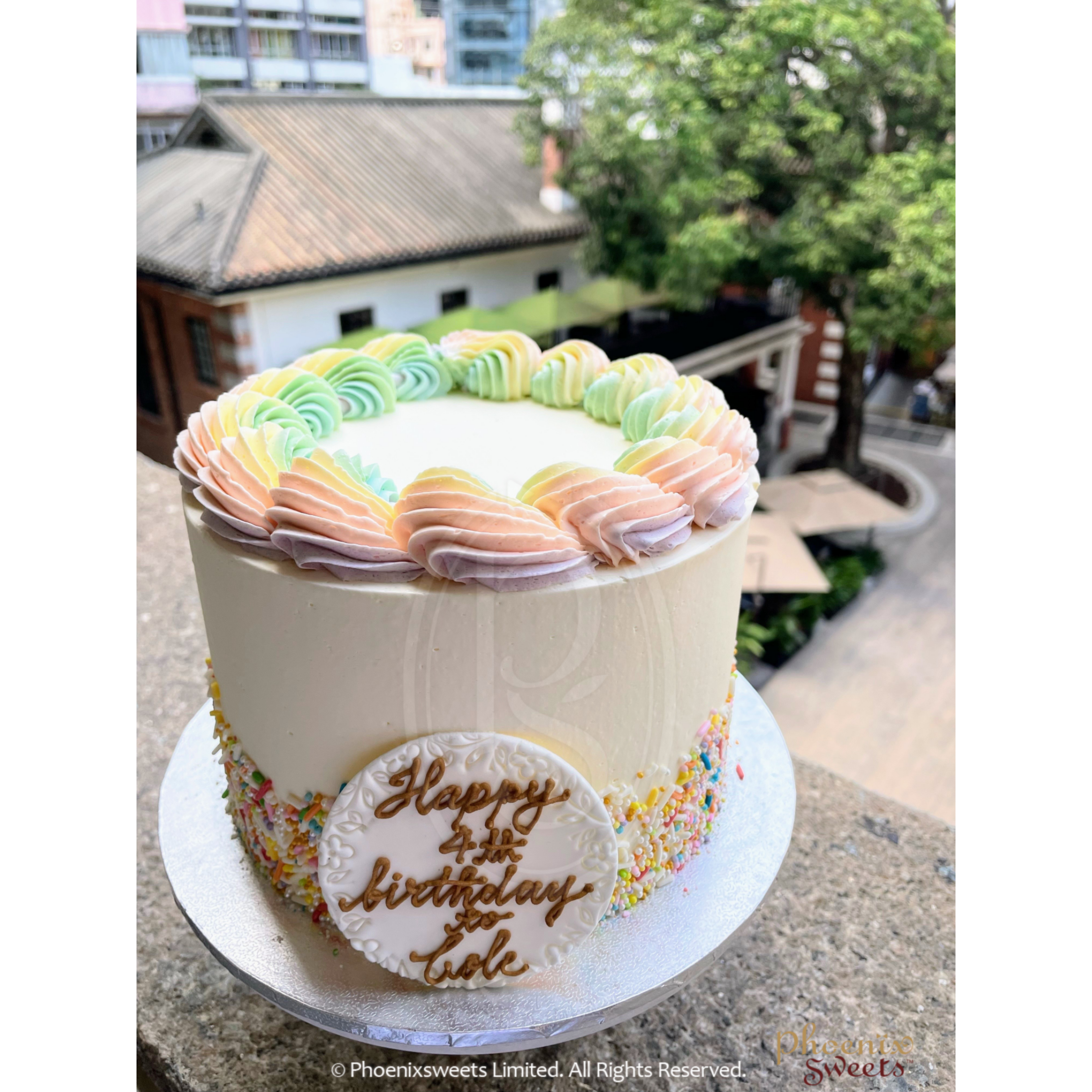 A multi color cake with an inverted cone on top with fondant made candies  on side – Creme Castle